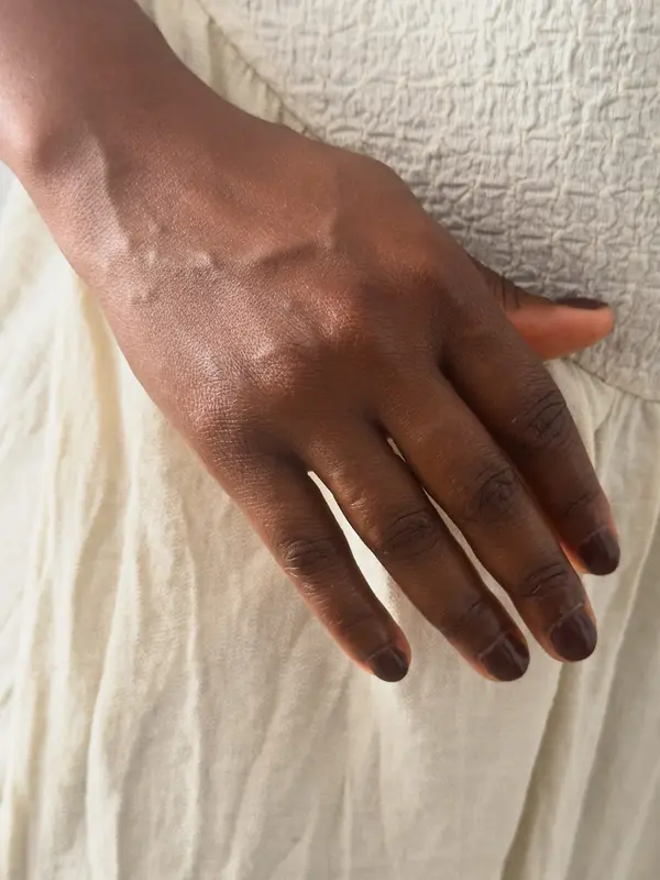 Main à la peau souple posée sur un drap de lin crème